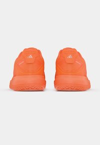 Φωτεινά πορτοκαλί αθλητικά παπούτσια Adidas Ubersonic, εμφανιζόμενα από πίσω σε απλό λευκό φόντο.