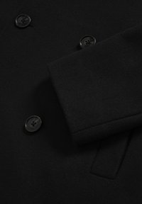 Čierny vlnenný kabát s hladkou textúrou, dvojradovým dizajnom a dvoma veľkými čiernymi gombíkmi vpredu.