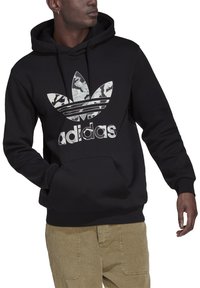 Felpa nera con cappuccio in materiale morbidissimo, caratterizzata da un logo Adidas a camouflage e un design con tre strisce. Include una tasca frontale e cappuccio con cordini.