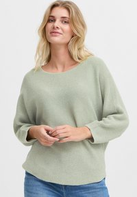 Maglione lavorato a maglia verde chiaro, con una vestibilità rilassata, scollo rotondo e maniche a tre quarti. Motivo testurizzato su tutta la superficie. Design casual.