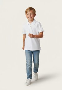 Biała koszulka polo z kołnierzykiem i detalem guzikowym, połączona z jasnoniebieskimi dżinsami i białymi sneakersami. Dziecko idzie.