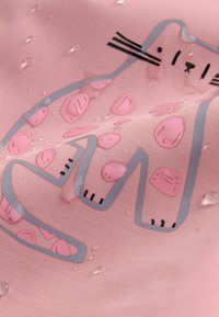 Rosa Stoff mit einem stilisierten Katzenumriss und Flecken, auf dem sich Wassertropfen bilden.