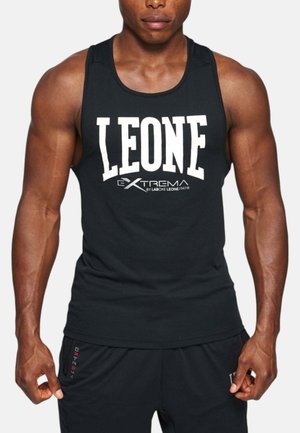 Uomo muscoloso che indossa una canotta nera senza maniche con grande scritta bianca "LEONE" e pantaloncini neri con il marchio "EXTREMA".