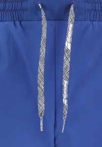 Blaue Sportshorts verfügen über einen elastischen Bund mit einem grau-weißen gestreiften Kordelzug. Die auffällige Markierung auf dem Kordelzug trägt den Schriftzug "Babolat".