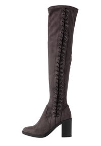 Botas de ante gris por encima de la rodilla con tacón cuadrado. Presentan detalles de cordones negros a lo largo del lado exterior y una forma de puntera suave.
