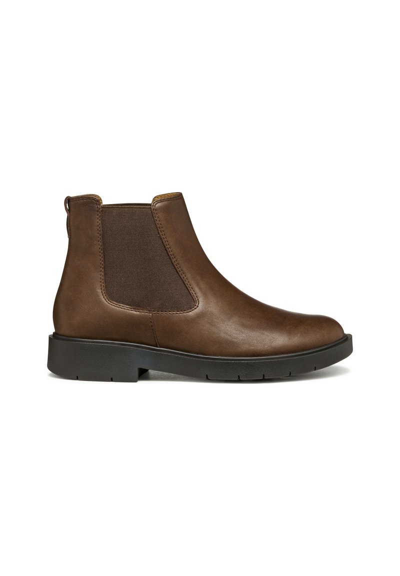 Bota Chelsea de cuero marrón con paneles laterales elásticos, puntera redondeada y suela de goma negra. Presenta una pestaña en la parte posterior para facilitar su colocación.