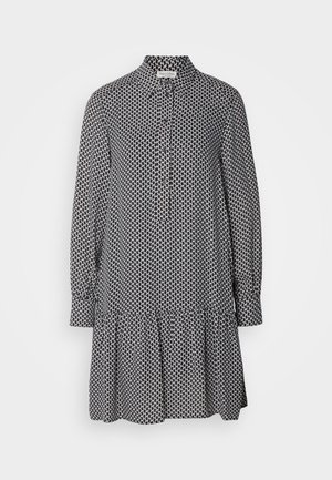 Fekete-fehér mintás ruhadarab, galléros nyakkal, hosszú ujjakkal és fodros szegéllyel, könnyű anyagból készült.