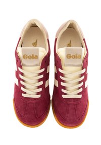 Maroon suede sneakers with cream accents, featuring lace-up design, white side stripes, and a brown rubber outsole. Logo on tongue.