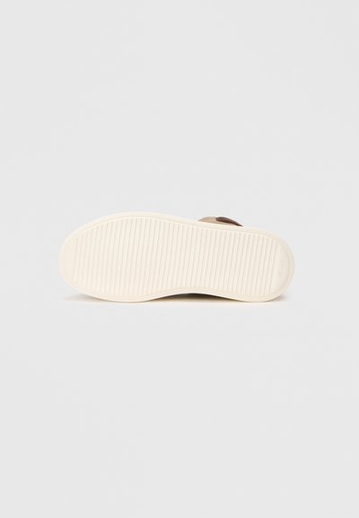 Suela de zapato de ante marrón con una superficie texturizada, que presenta estrías verticales para mayor agarre y una entresuela de goma blanca para amortiguación.