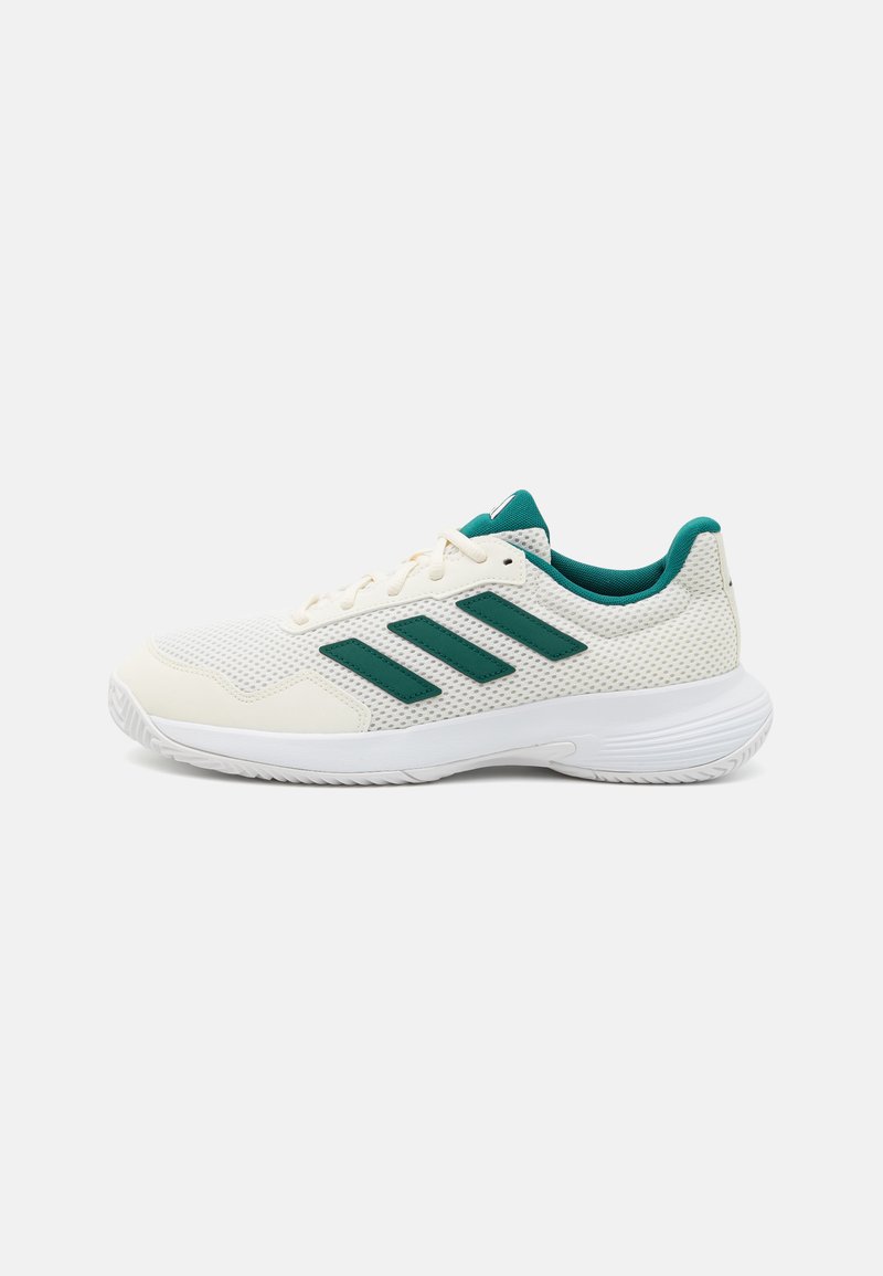 Zapato deportivo blanco con detalles verdes, parte superior de malla, diseño de tres franjas y suela acolchada para comodidad y soporte.