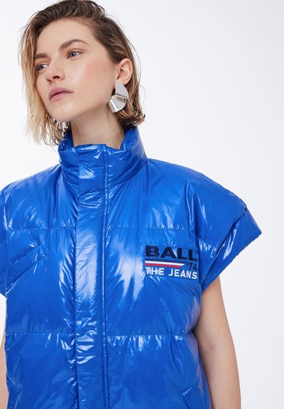Blue puffer vest with a glossy finish, high collar, short sleeves, and a patch featuring "BALL" and "THE JEANS." Textured surface, lightweight design.