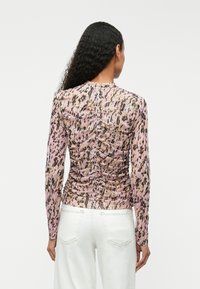 Długo rękawowy top z przejrzystego, lekkiego materiału z różowym, beżowym i czarnym wzorem zwierzęcym oraz marszczeniami z tyłu.