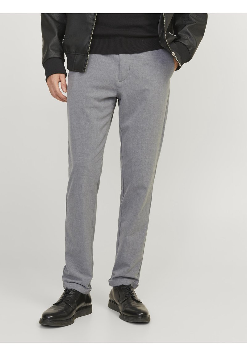 Pantalons de costume gris en tissu texturé, coupe droite, avec une ceinture lisse et des poches latérales, assortis à des chaussures à lacets noires.