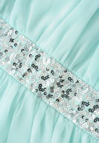 Abito verde menta fluido con una cintura decorata da paillettes con sequenze alternate di paillettes argentate e nere, creando un accento scintillante.