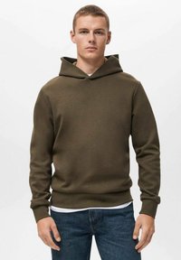 Olijfgroene hoodie gemaakt van zachte, textuurstof; heeft een grote capuchon, geribbelde manchetten en een rechte zoom. Draagt over een wit shirt.