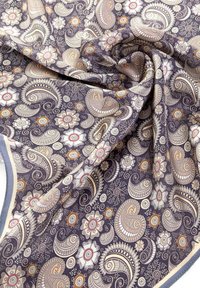 Patroonstof met paisley- en bloemdessins in beige, crème en oranje tinten op een donkerpaarse achtergrond met een gladde textuur.