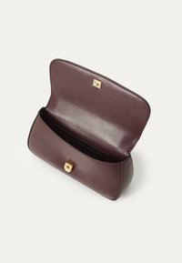 Clutch din piele burgundie cu o textură netedă, cu închidere aurie și un interior deschis care dezvăluie un suport pentru carduri negru.
