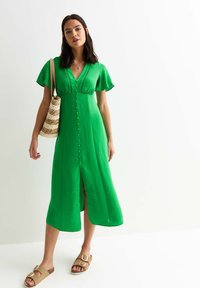 Vestido midi verde con mangas cortas acampanadas, escote en V, cierre de botones en el frente y una abertura en el dobladillo. La textura parece ligera.