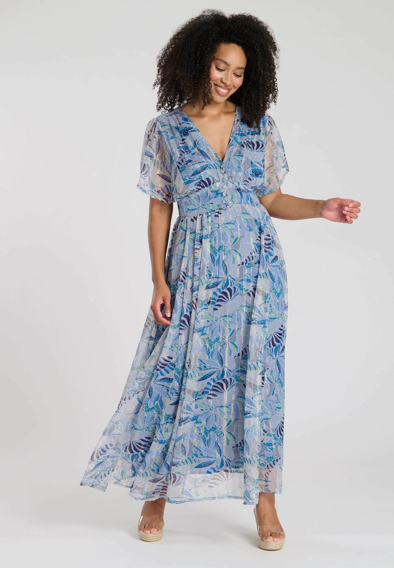 Robe maxi en tissu bleu clair avec des motifs de feuillage dans des bleus et verts plus foncés, manches courtes et décolleté en V. Design fluide.