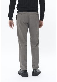 Pantaloni gri rayati cu o croială slim, având două buzunare la spate închise cu butoane și asortați cu pantofi negri. Material texturat.