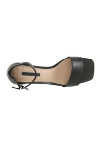 Musta nahkainen avonainen korkokenkä neliön muotoisella varvaspäällä, säädettävällä nilkkahihnalla ja sileällä beige pohjalla.