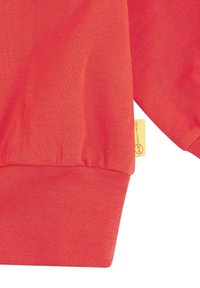 Rode sweatshirt met ribbels aan de mouwen en onderkant, gemaakt van zachte katoen en met een goed zichtbaar geel merklabel aan de linkerkant.