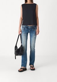 Czarny prążkowany top bez rękawów, jasnoniebieskie podniszczone dżinsy, czarna torba na ramię i czarne klapki. Casualowa stylizacja z kontrastującymi fakturami.