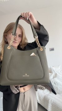 Olivengrøn håndtaske med en tekstureret overflade, prydet med guldkæde-detaljer og en logo. Tasken har en rundet form og dobbelte håndtag.