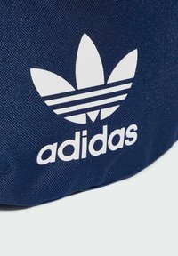Navy blue textile bag featuring a large white Adidas logo with three stripes and a trefoil design, showcasing a textured surface.