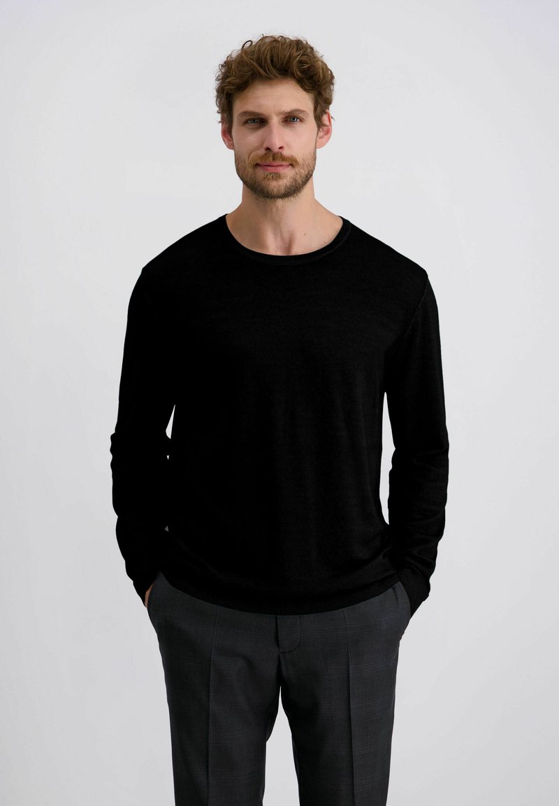 Schwarzes Langarmshirt mit rundem Ausschnitt, aus einem glatten Stoff, kombiniert mit grauen gemusterten Hosen. Einfaches Design ohne sichtbare Logos.