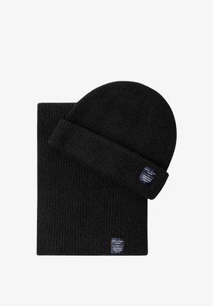 Gorro de punto acanalado negro y bufanda a juego con pequeñas etiquetas rectangulares de la marca cosidas en el puño y el borde de la bufanda.
