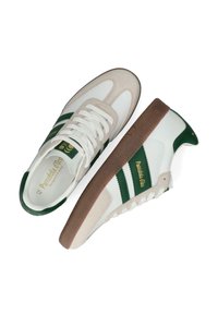 Vita och gröna sneakers med en mocka-tå och hälen. Har två gröna ränder, texturerad gummisula och guld logo-detaljer på tungan.