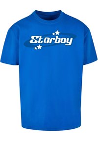 Zila kokvilnas T-krekls ar baltu tekstu "Starboy" un zilu vērpeti un maziem zvaigznēm. Īsas piedurknes, apaļa kakla izgriezums.