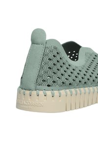 Grüne Wildleder Sneaker mit einem Wellenmuster an der Seite, beiger Gummisohle und einer hinteren Lasche für einfaches Anziehen. Strukturierte Oberfläche insgesamt.