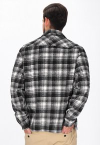 Musta-valkoinen ruudullinen flanellipaita, jossa on levitettävä kaulus, pitkähihaisena ja nappikiinnityksellä varustetut hihansuut. Pehmeä, teksturoidu kangas. Takakatsaus esitetty.