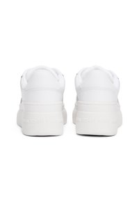 Białe trampki z gładką syntetyczną cholewką, wyściełanym kołnierzem i teksturowaną gumową podeszwą z logo "TOMMY JEANS" na pięcie.