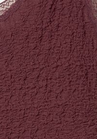 Burgundy texturerat tyg med ett skrynkligt mönster, med en delikat spetskant längs halsringningen. Mjukt och lätt material.