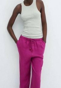 Grijze geribbelde tanktop gecombineerd met fuchsia drawstring broek met een ontspannen pasvorm en kraalaccenten op de koorden.