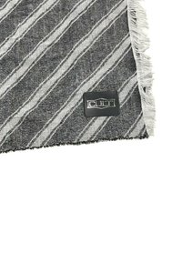 Tessuto a strisce bianche e nere con bordo frangiato e un'etichetta tessuta rettangolare con la scritta "CULT" in lettere grassetto.