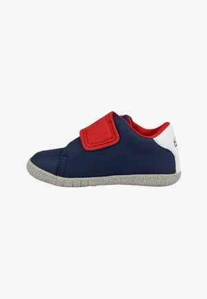 Zapatilla de color azul marino con acentos rojos, una correa de Velcro y suela texturizada gris. Material superior suave con un diseño de corte bajo.