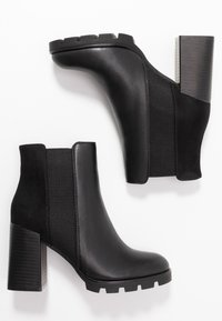 Mustat nilkkurit, joissa yhdistyvät sileä nahka ja teksturoitu mokkanahka, paksu korko ja kumipohja lisäämässä pitoa.