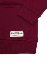 Vinröd huvtröja med ribbade muddar och nederkant, en känguruficka och en sydd etikett som säger "Band of Rascals" i vitt.