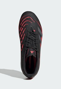 Black soccer cleat with red accents, textured synthetic upper, flat laces, and prominent stripes; designed for performance on the field.