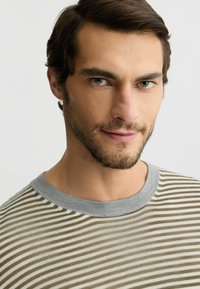 Gestreiftes Hemd in Beige- und Grüntönen mit einem grauen Ripp-Ausschnitt. Verfügt über feine horizontale Streifen auf einem leichten Stoff.