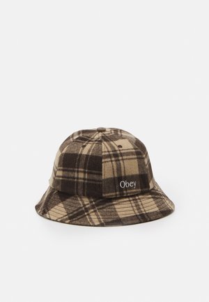 Bruine en beige geruite bucket hat van zacht materiaal, met een platte kroon, brede rand en geborduurd "Obey" logo aan de zijkant.