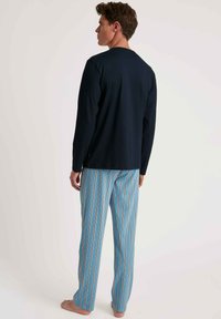 Navy lange mouwen top met ronde hals, gecombineerd met multicolored gestreepte pyjamabroek met een relaxte pasvorm en lichtgewicht stof.