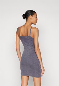 Rūbų suktukas purpurinės savo atspalvio medžiagos su plonomis petnešėlėmis ir prigludusia siluetu, su logotipo detale gale.