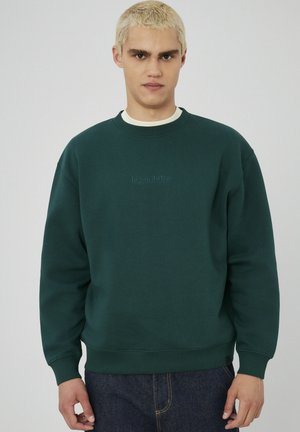 Sweatshirt vert en mélange de coton, avec un col ras du cou, des poignets côtelés et un logo brodé discret à l'avant. Matière lourde, coupe décontractée.