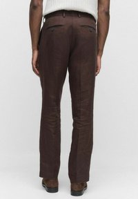 Bruna linbyxor med slim fit, två bakfickor med knappstängning och ett slätt texturerat tyg.