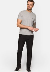 Szara bawełniana koszulka z krótkimi rękawami i okrągłym dekoltem. W połączeniu z czarnymi spodniami slim-fit i czarnymi trampkami z białą podeszwą.